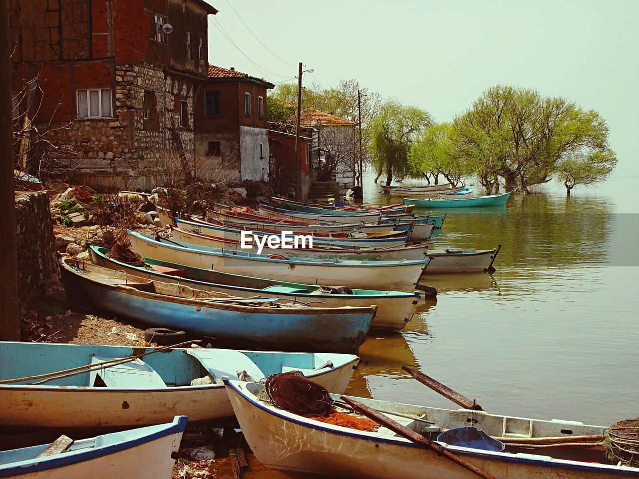 Boats moored in lake by buildings against sky