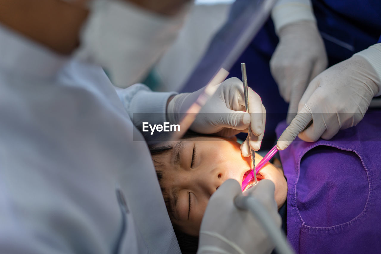 Hand of doctor dentist is working on the teeth of asian little kid 6 year patient in dental clinic
