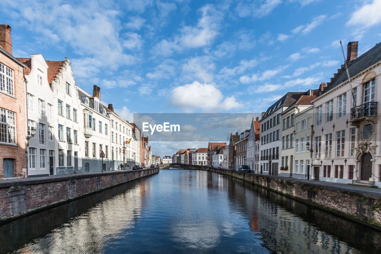 Canal amidst buildings in city against sky