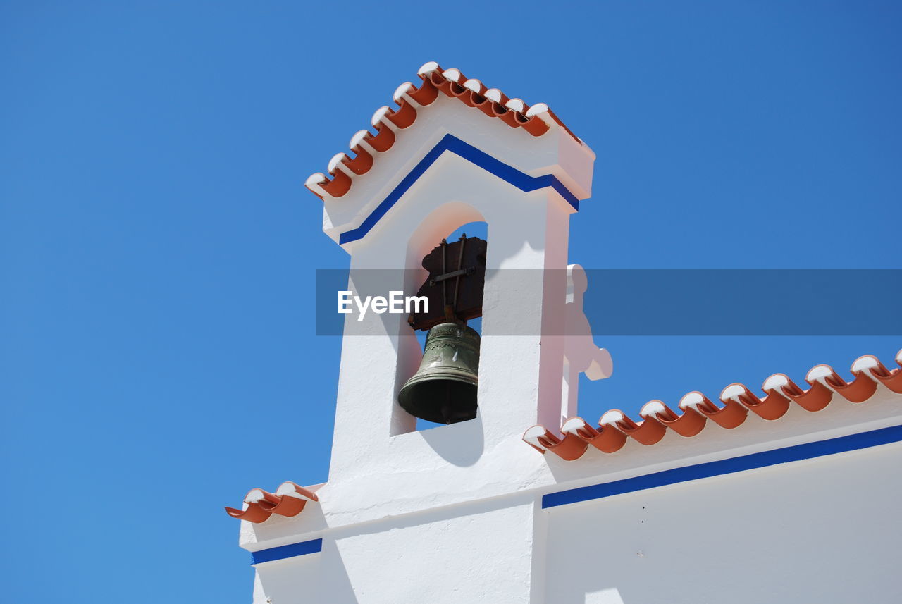 Low angle view of bell on church against clear blue sky