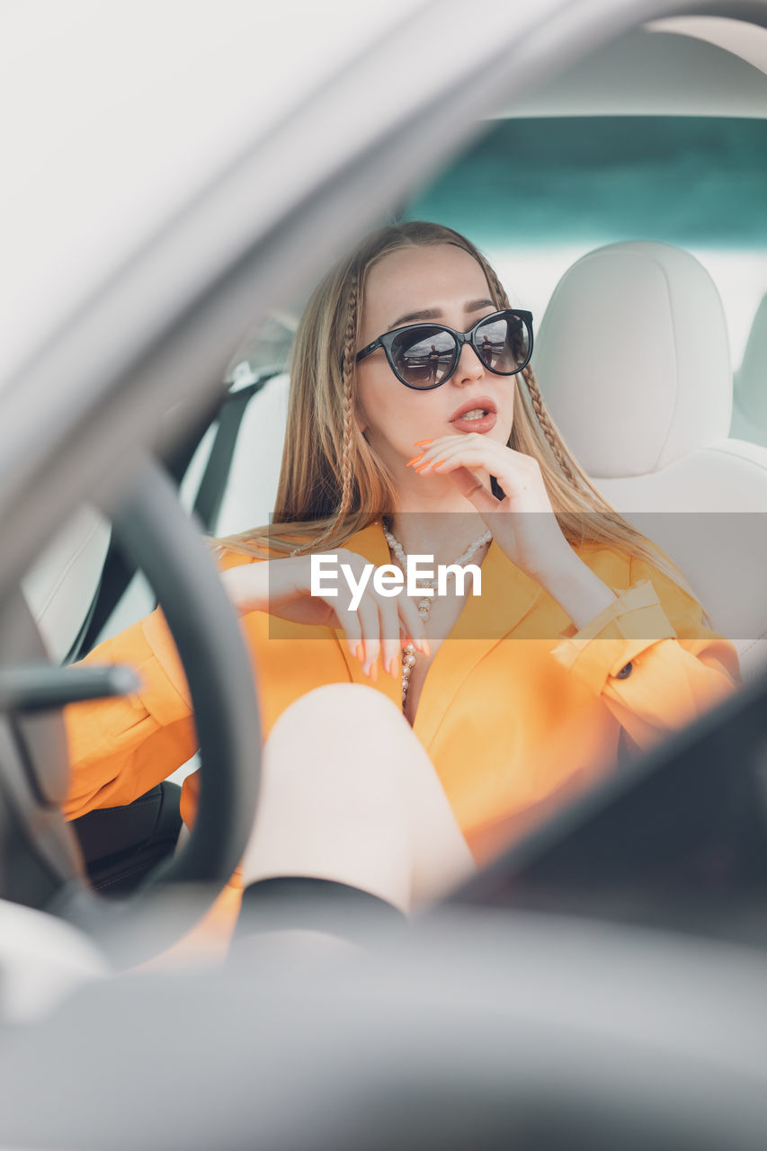 Side view of young woman sitting on side-view mirror