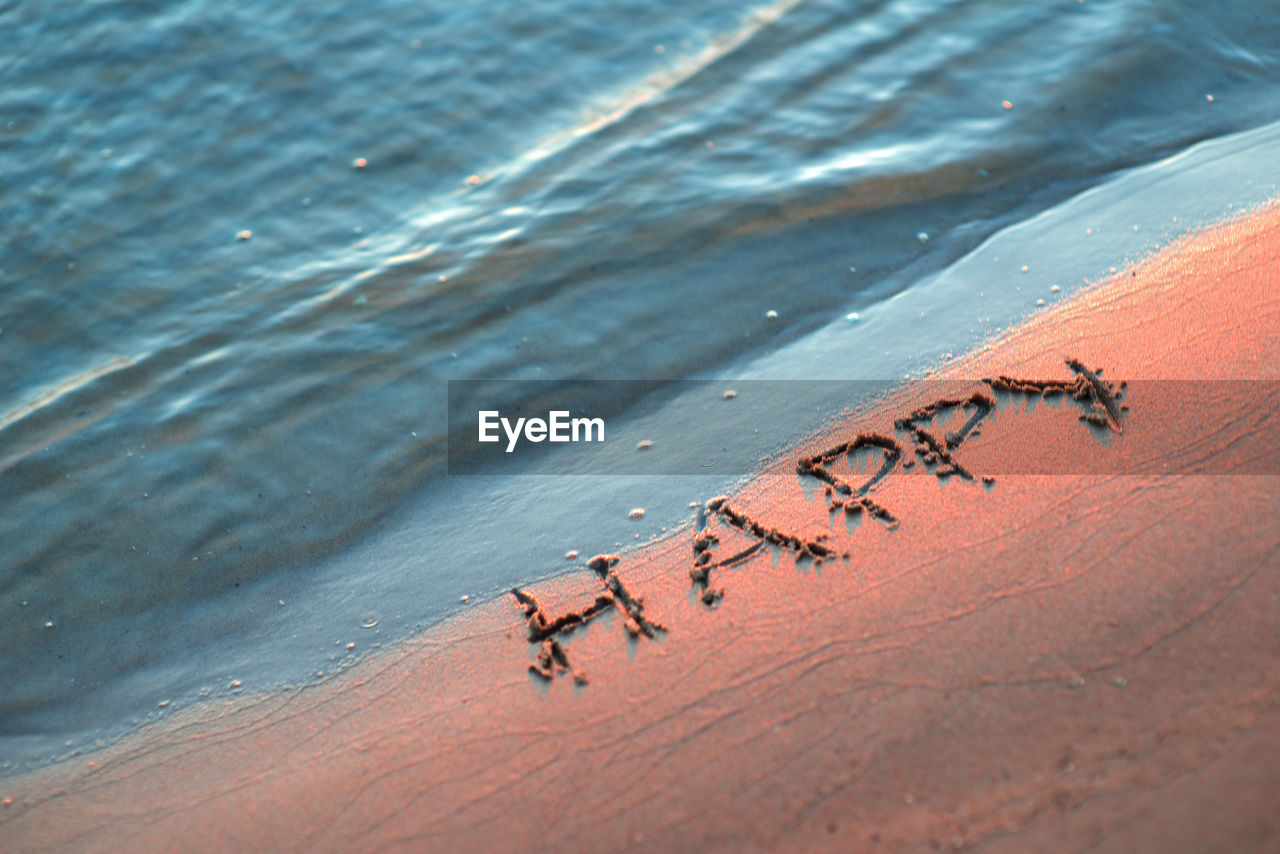 High angle view of happy text on shore at beach
