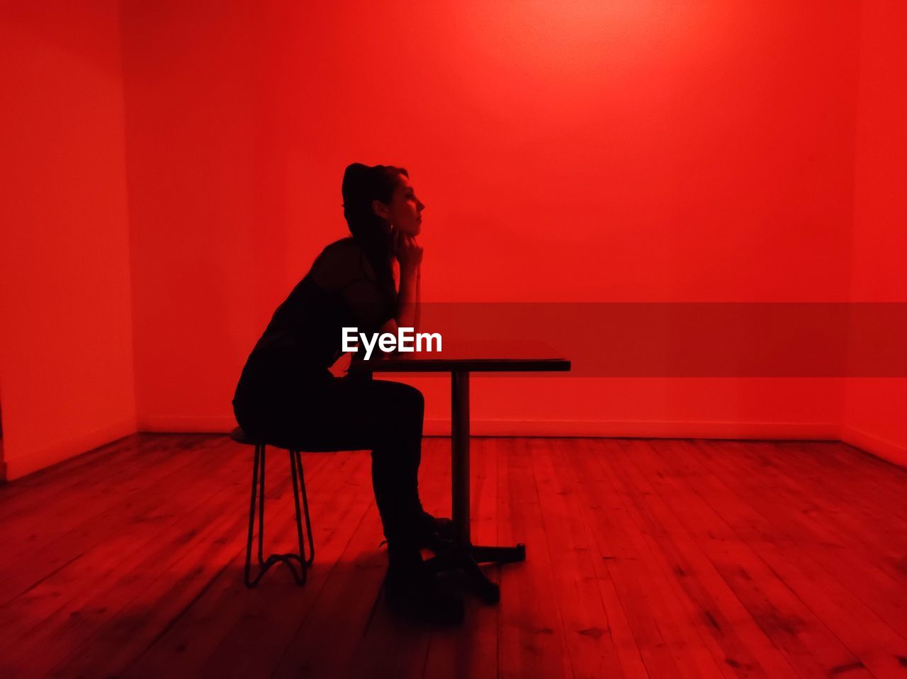 Side view of woman sitting on chair against wall