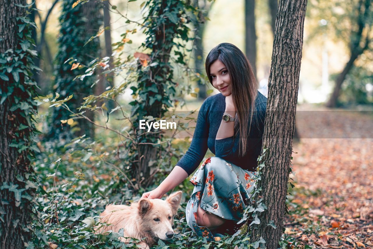 YOUNG WOMAN WITH DOG ON TREE