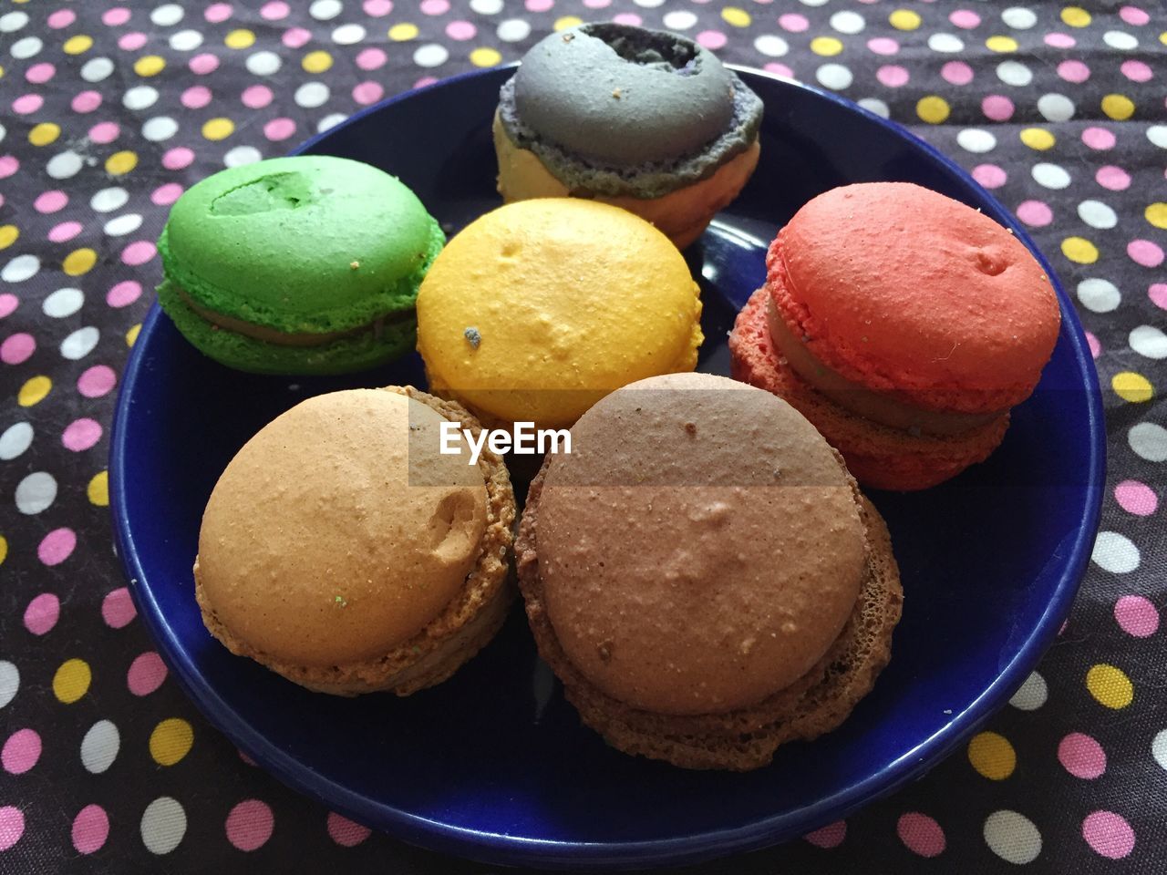High angle view of colorful macaroons in plate on tablecloth