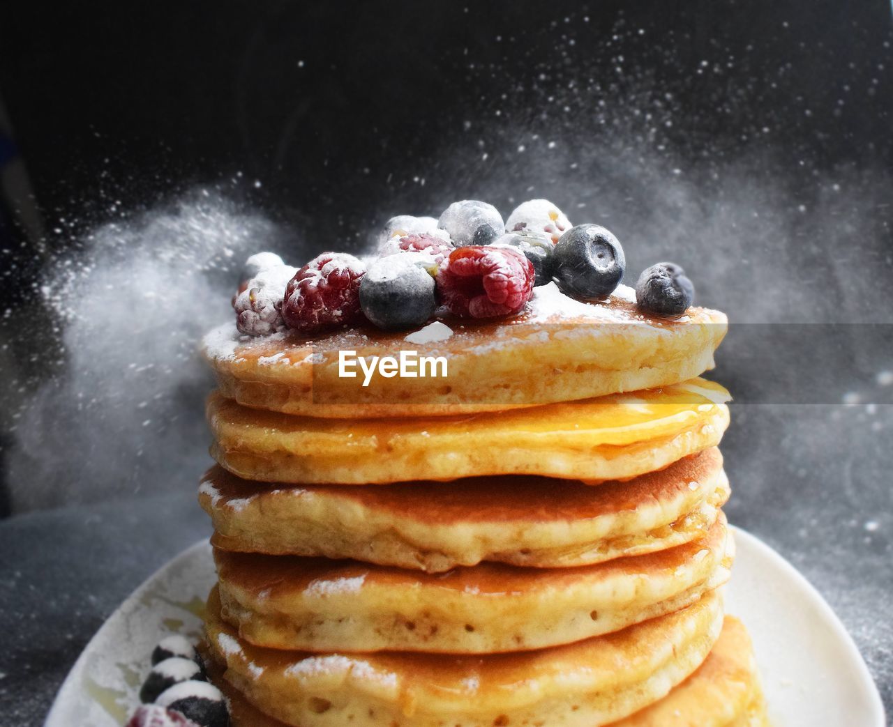 Close-up of pancakes stacked in plate against black background