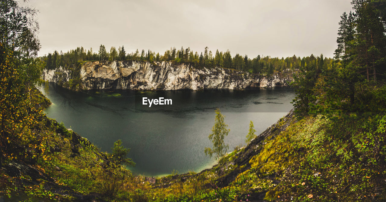 Scenic view of trees on cliff against sky