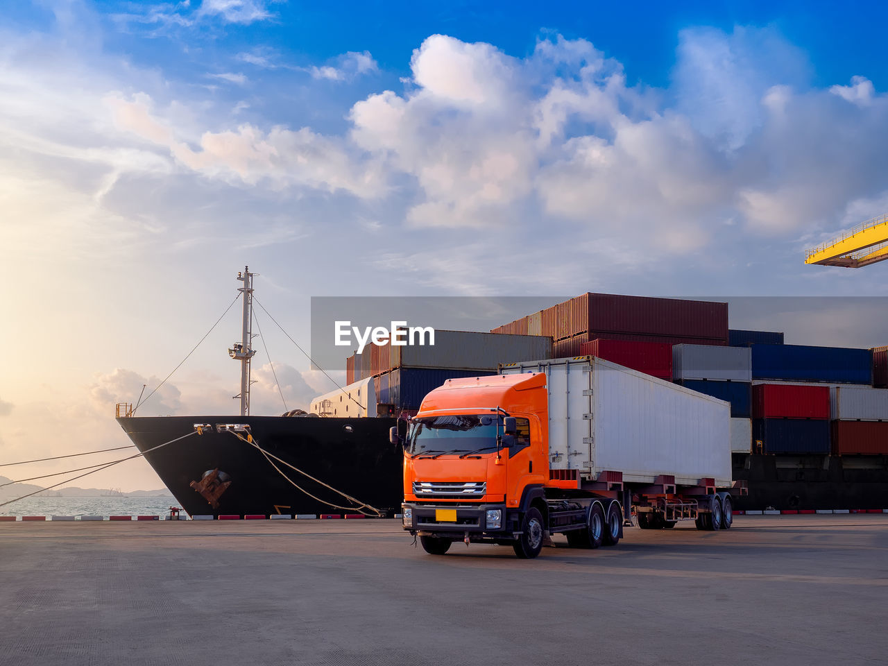 Truck on road against ship and cloudy sky