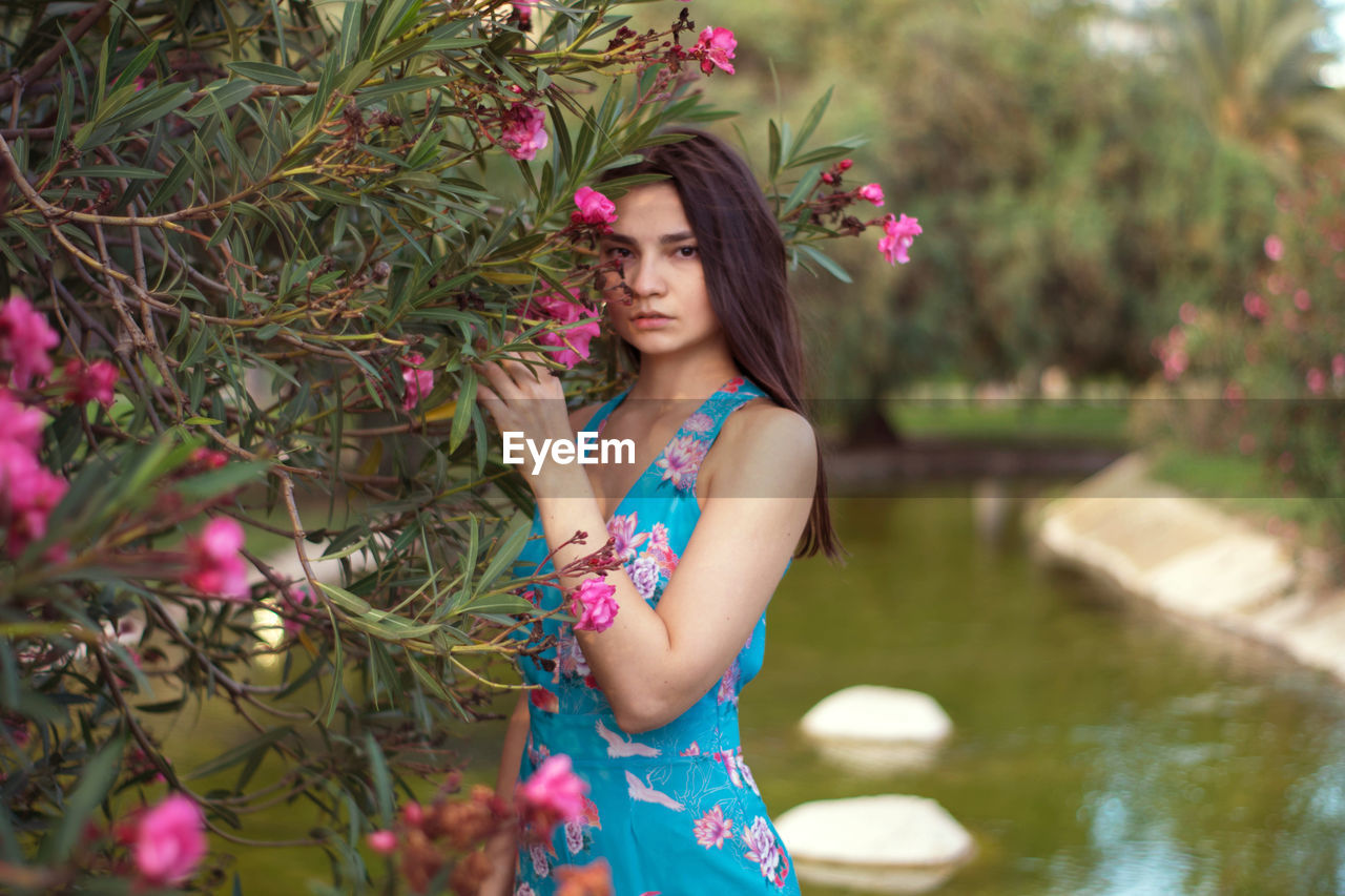 Portrait of a beautiful young woman standing by plants in park