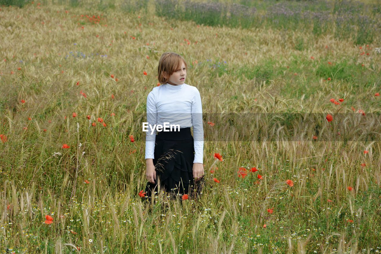 Girl standing amidst flowers on field