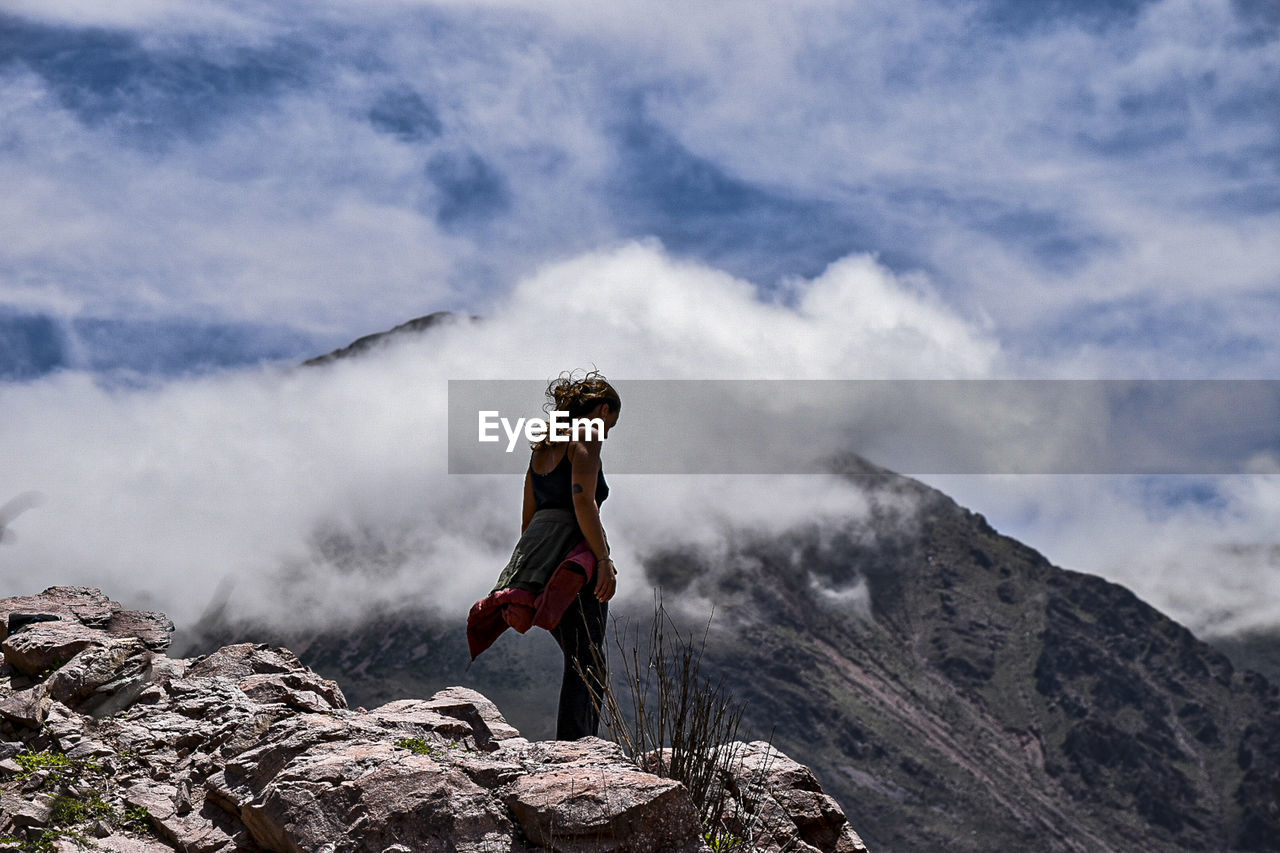 Man standing on rock against sky