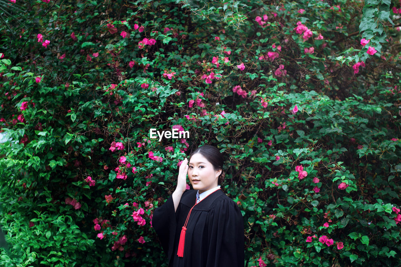 Portrait of beautiful woman standing by flowering plants