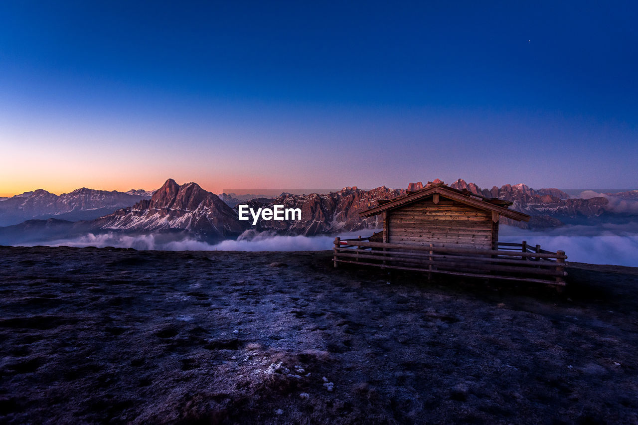 Scenic view of sea and snowcapped mountains against blue sky during sunset
