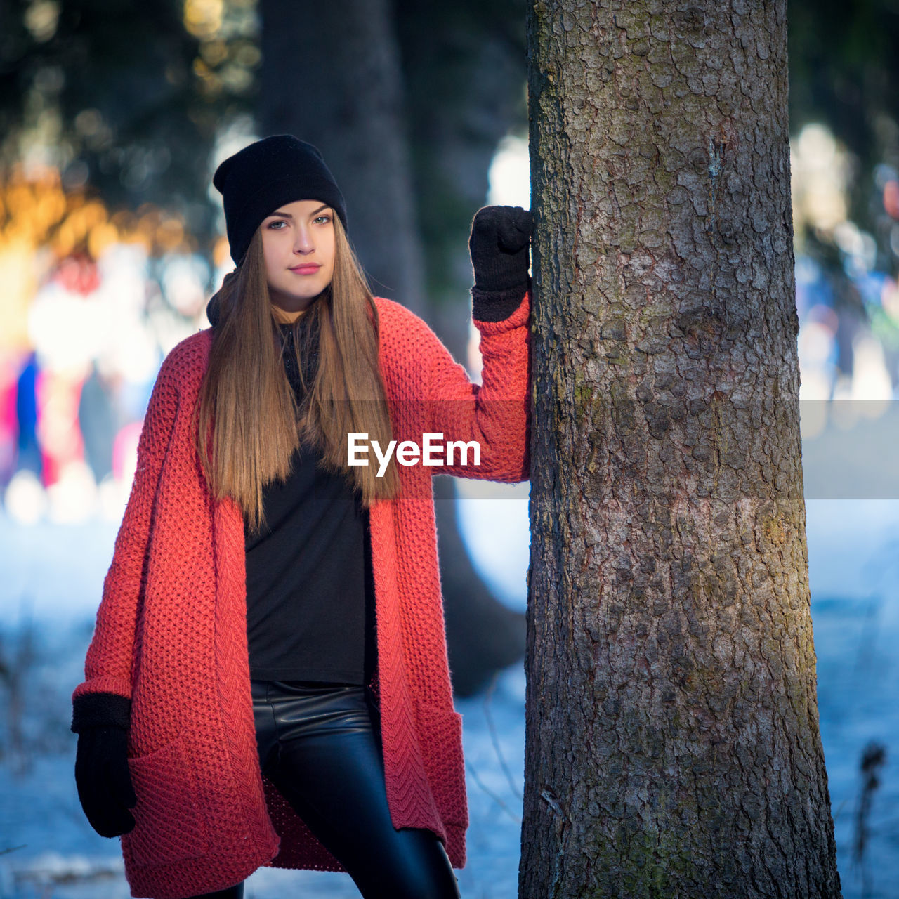 Portrait of young beautiful woman wearing warm clothing standing by tree during winter