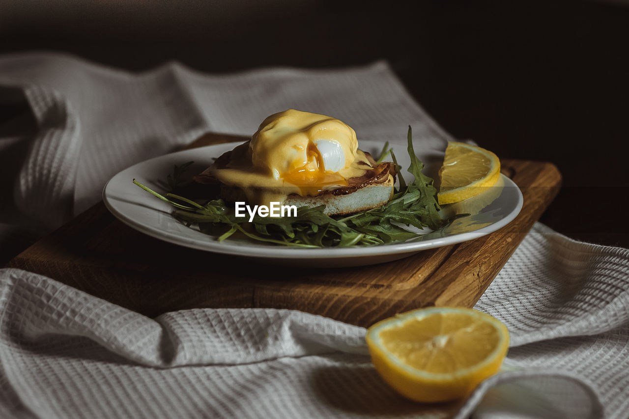 Eggs benedict and poached hollandaise sauce with arugula and lemon. delicious food for breakfast. 