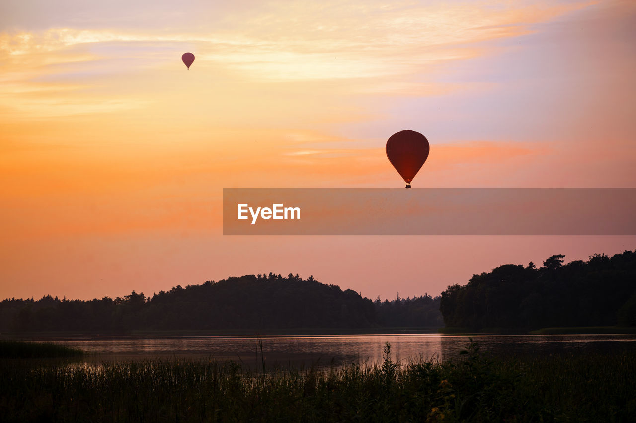 HOT AIR BALLOON FLYING OVER LAKE DURING SUNSET