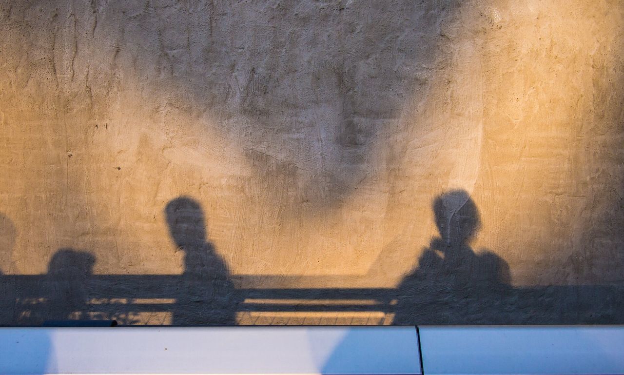 People shadows casted on building wall at sunset