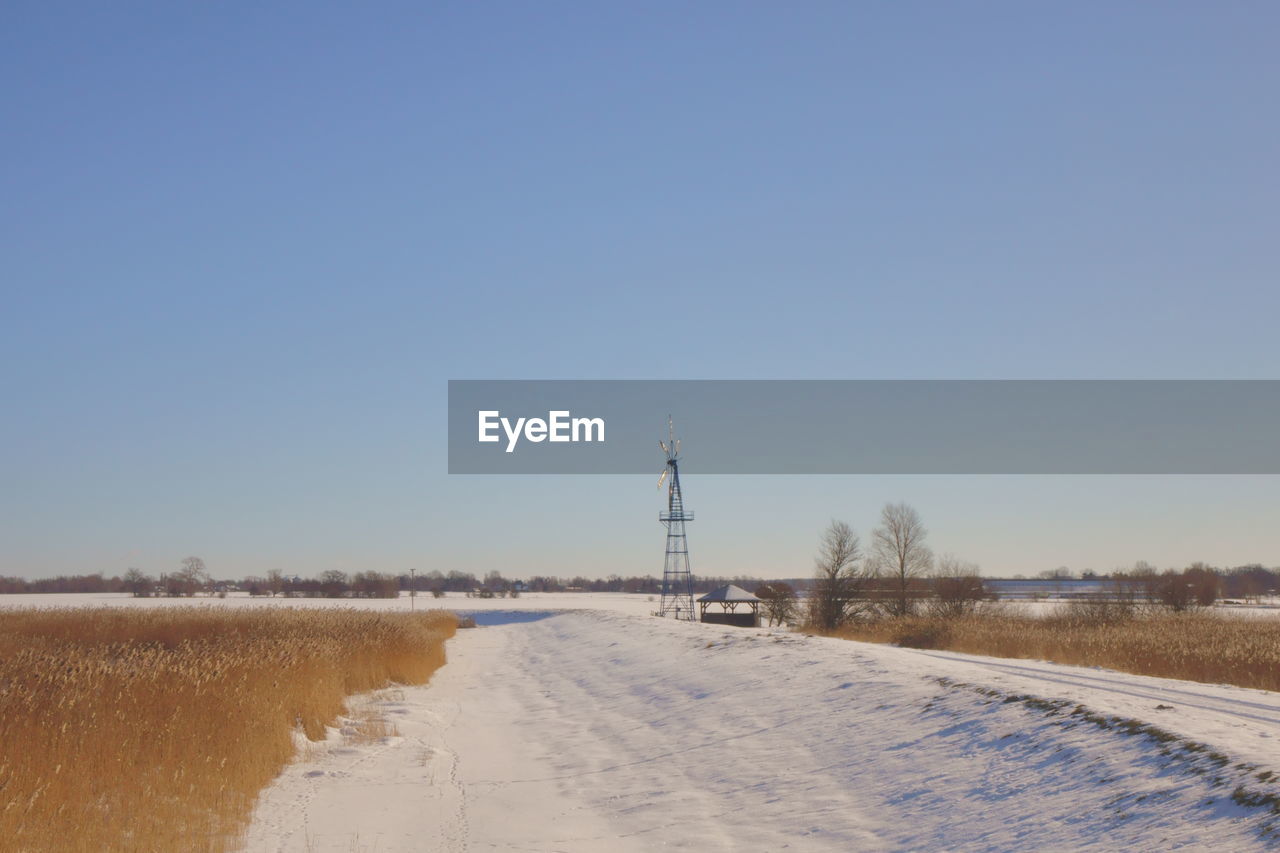 SNOW COVERED ROAD BY LAND AGAINST SKY