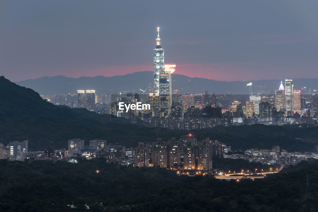 Illuminated buildings in city against sky at night