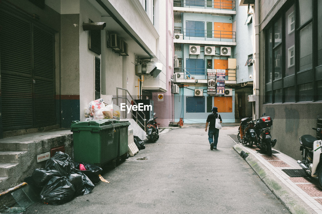 Rear view of man walking on street against building