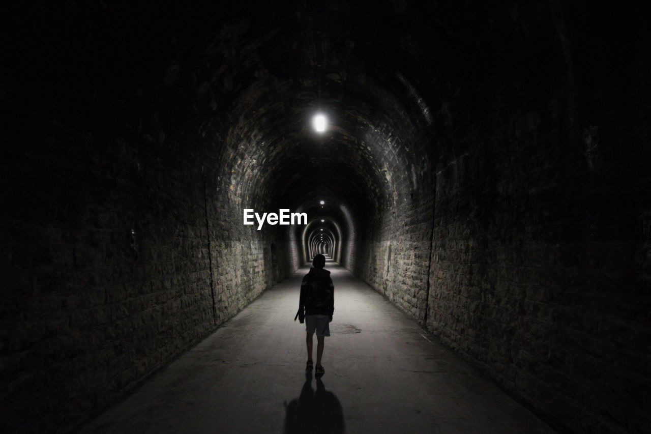 Rear view of man standing in tunnel