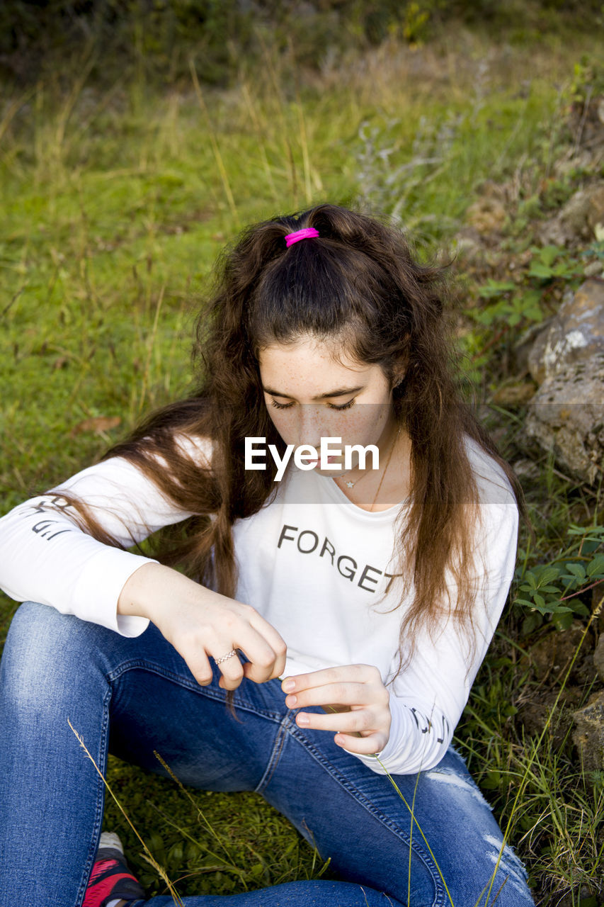 High angle view of teenage girl sitting on field