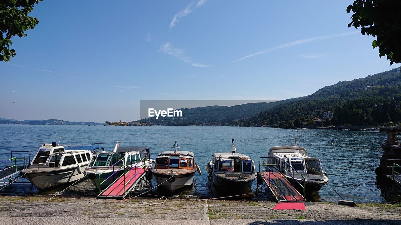 BOATS MOORED ON SHORE AGAINST SKY