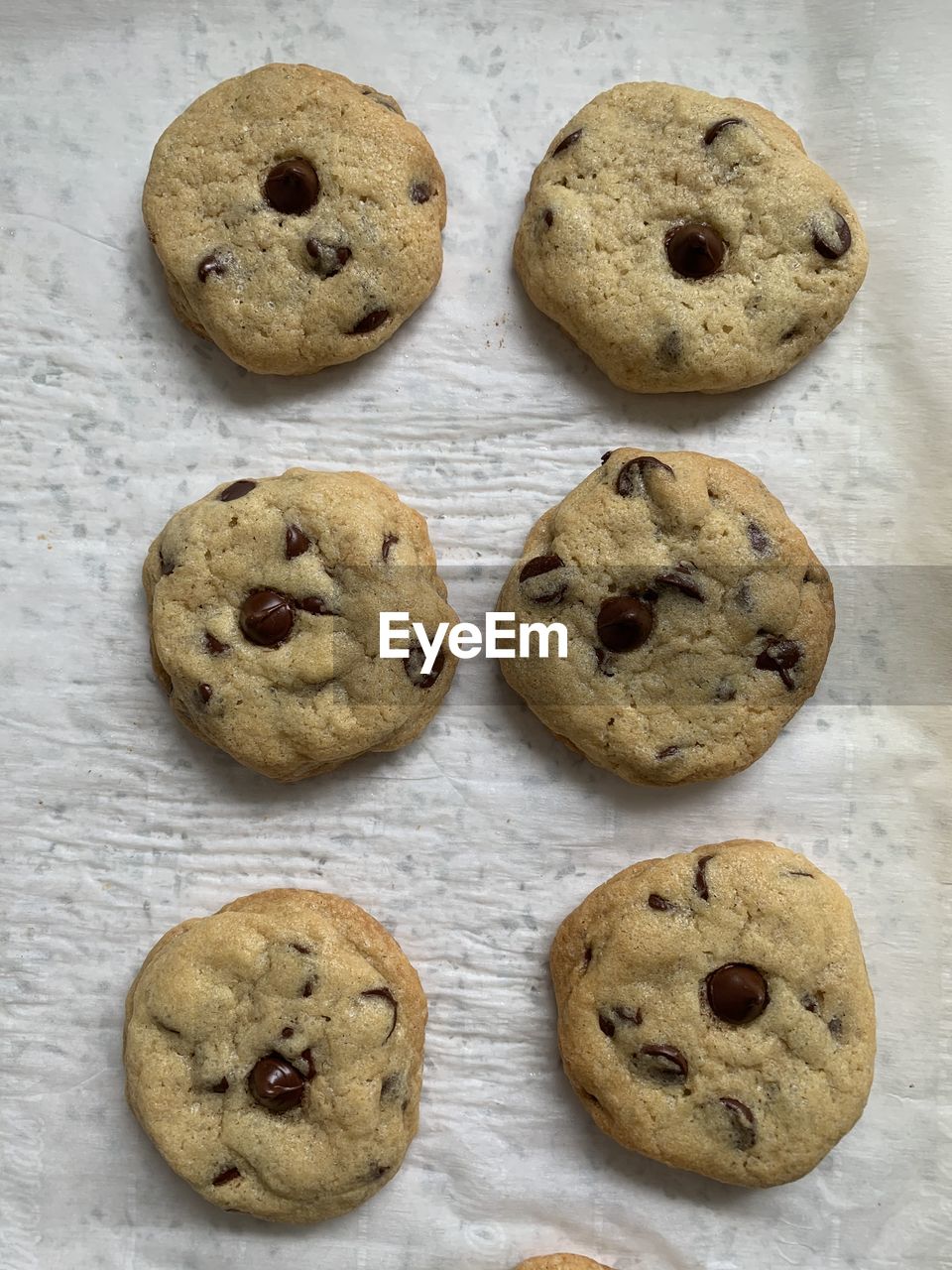 Chocoate chip cookies cooking on parchment paper