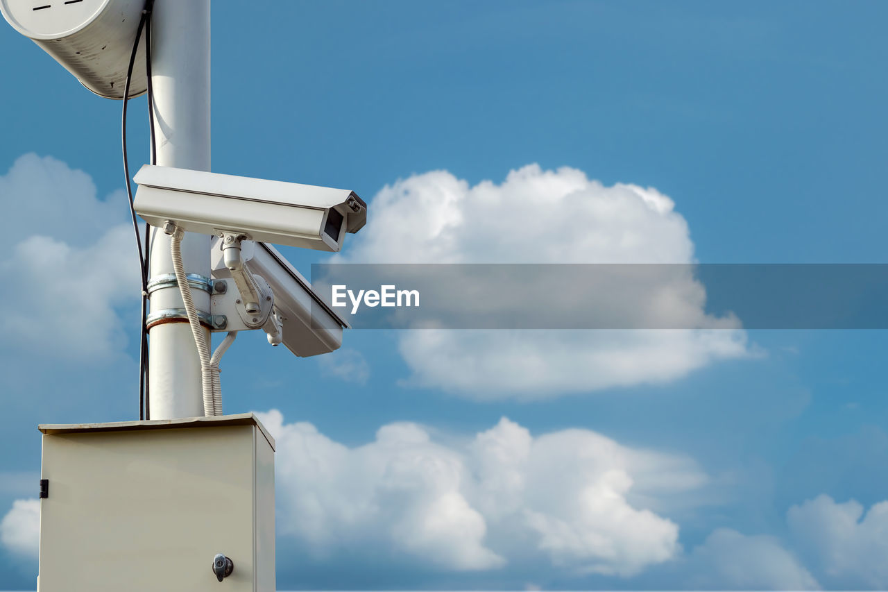 Cctv security camera isolated on blue sky background.