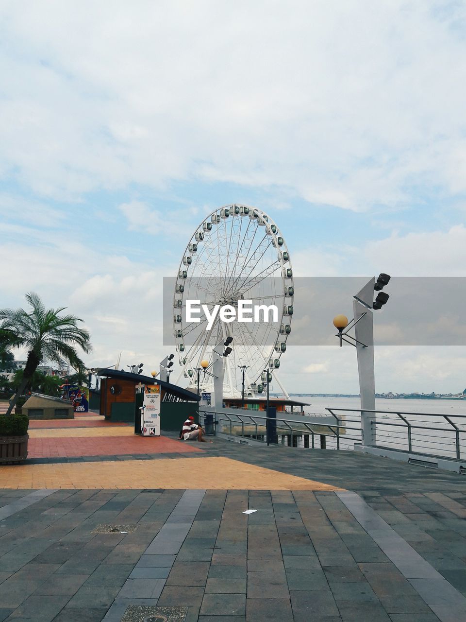 Ferris wheel by river in city against sky