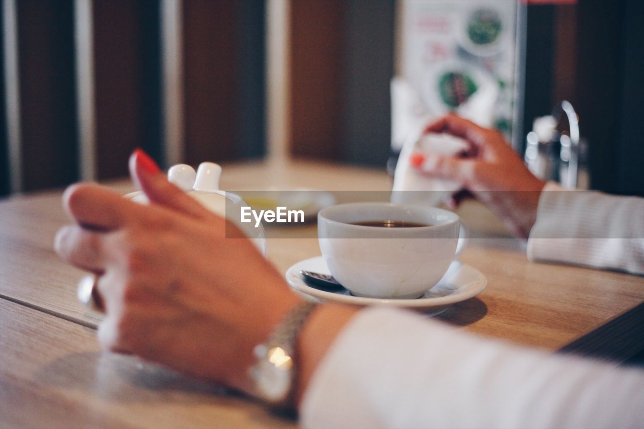 Cropped image of woman having coffee in cafe