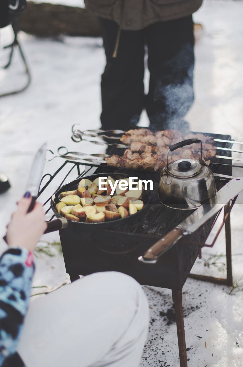 Cropped image of woman preparing food on barbeque grill