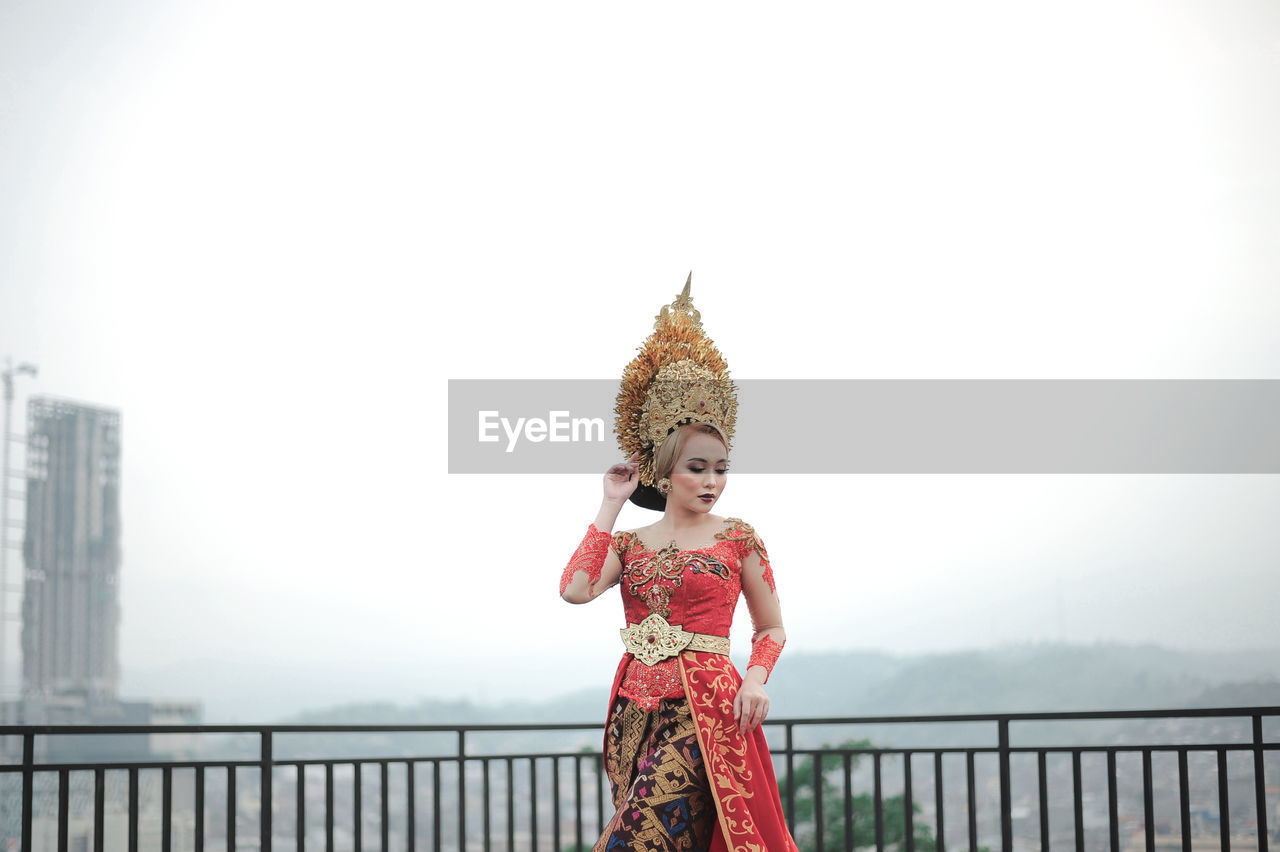 Portrait of woman with custom indonesia traditional wedding standing against railing