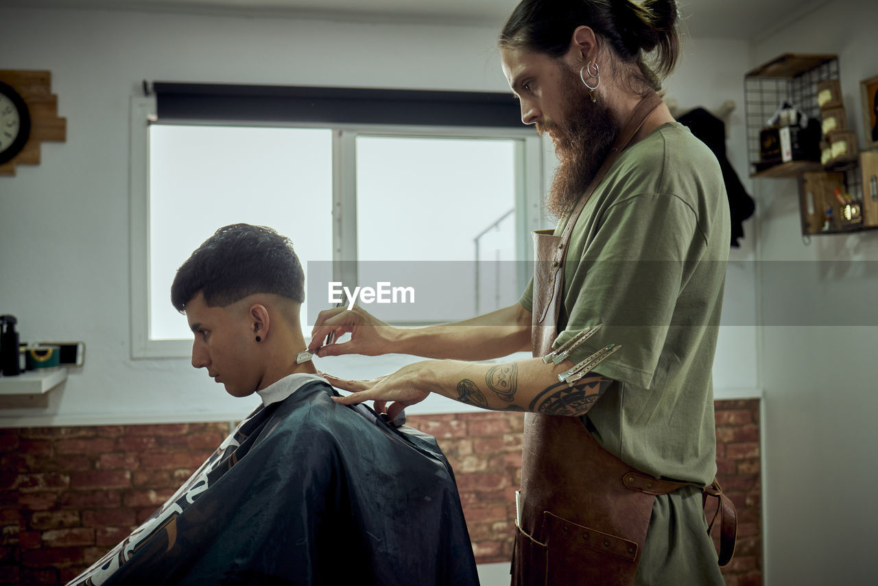 A hairdresser working with a knife on a client