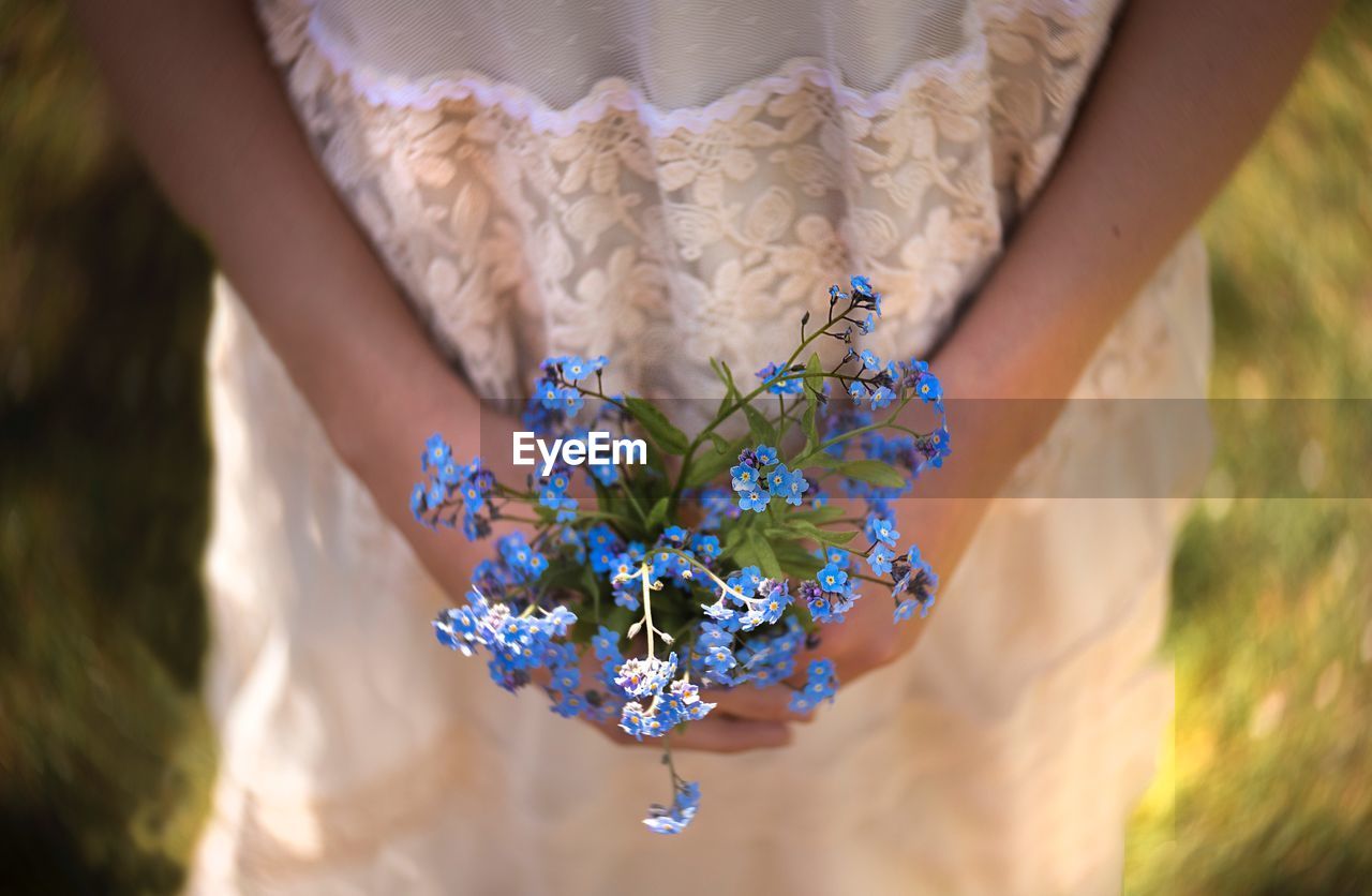 Midsection of girl holding flowering plant