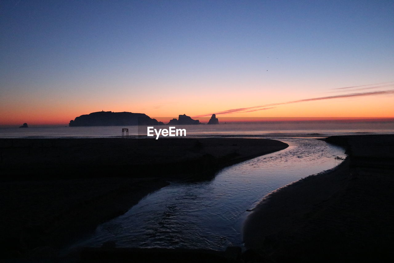 Scenic view of beach against clear sky during sunset