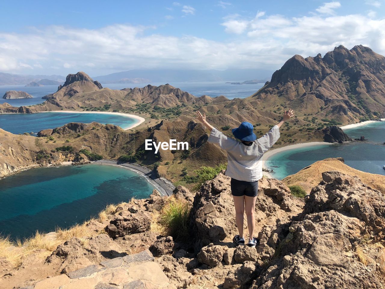 Rear view of woman standing on cliff against sea