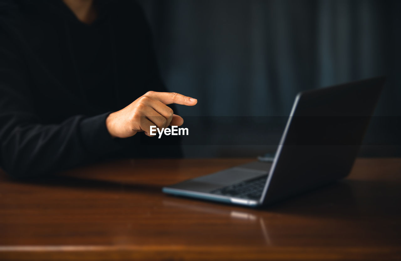 midsection of businessman using laptop at table