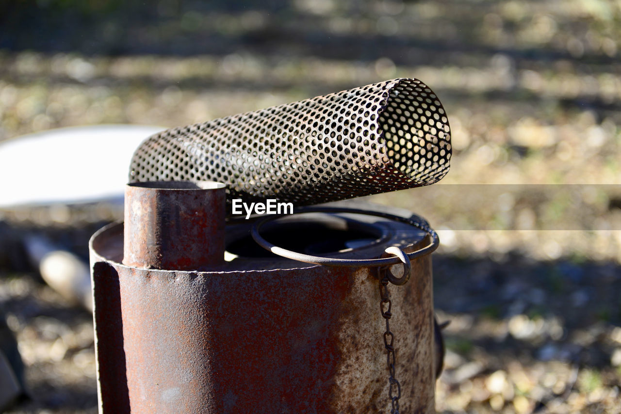CLOSE-UP OF OLD RUSTY METAL ON FIELD BY LAND