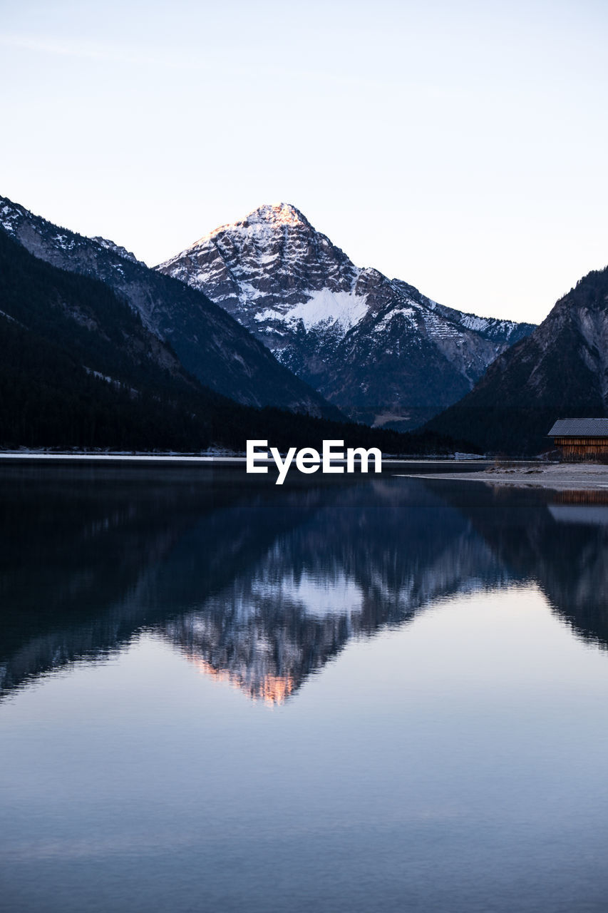 Scenic view of lake by snowcapped mountains against sky