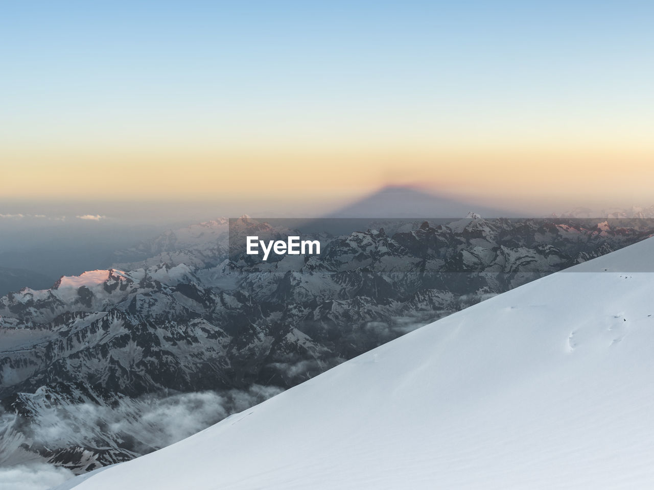 SNOW COVERED LANDSCAPE AGAINST SKY DURING SUNSET