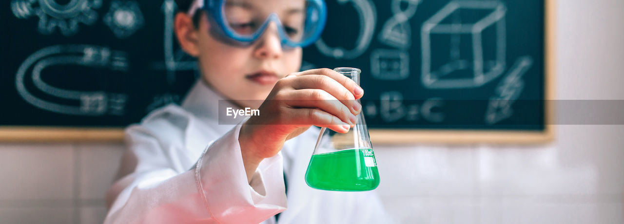 Cute boy examining chemical in classroom