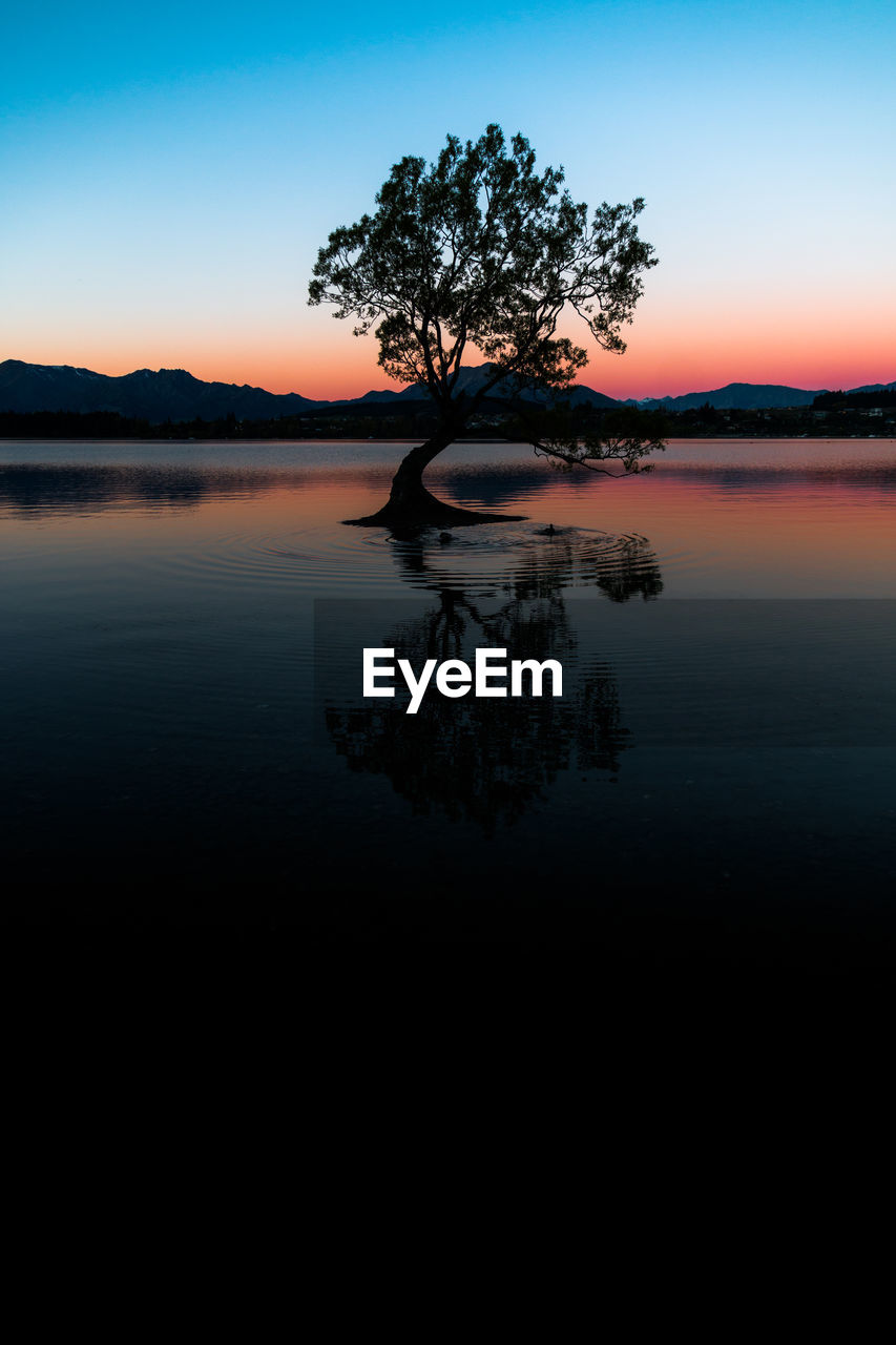 SCENIC VIEW OF LAKE AGAINST SKY AT SUNSET