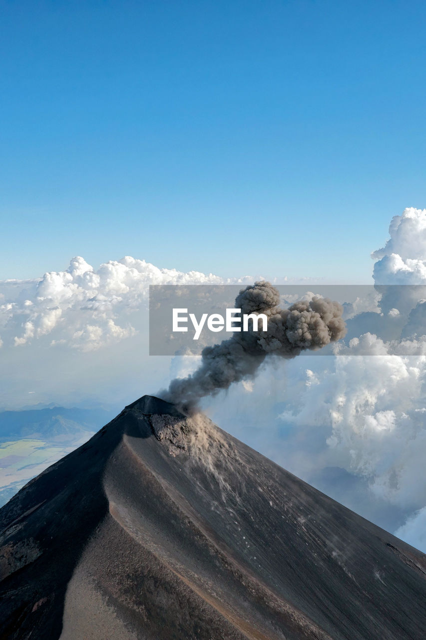 View of smoke emitting from volcanic mountain against sky