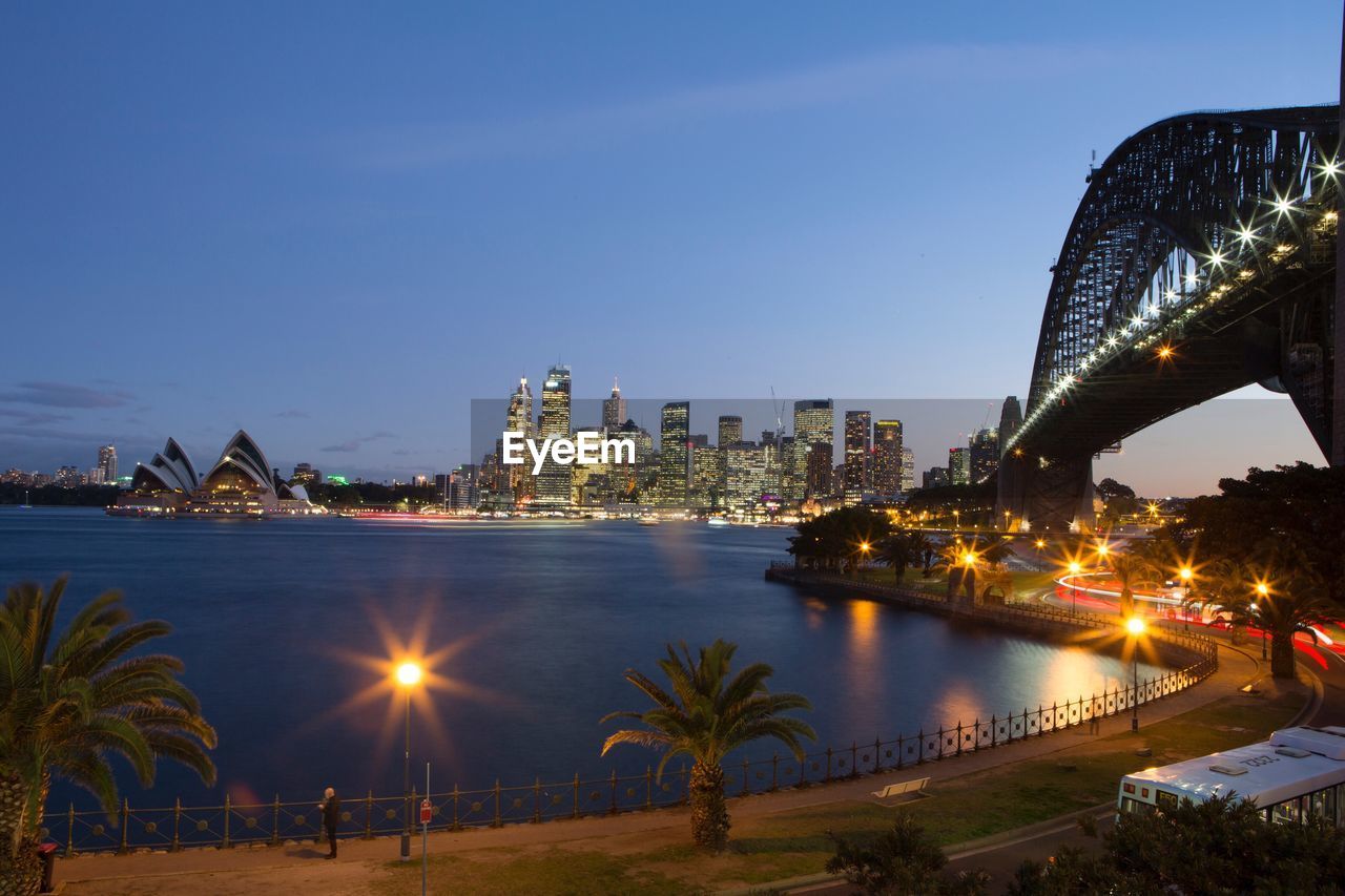 Illuminated city and sydney harbor bridge at night