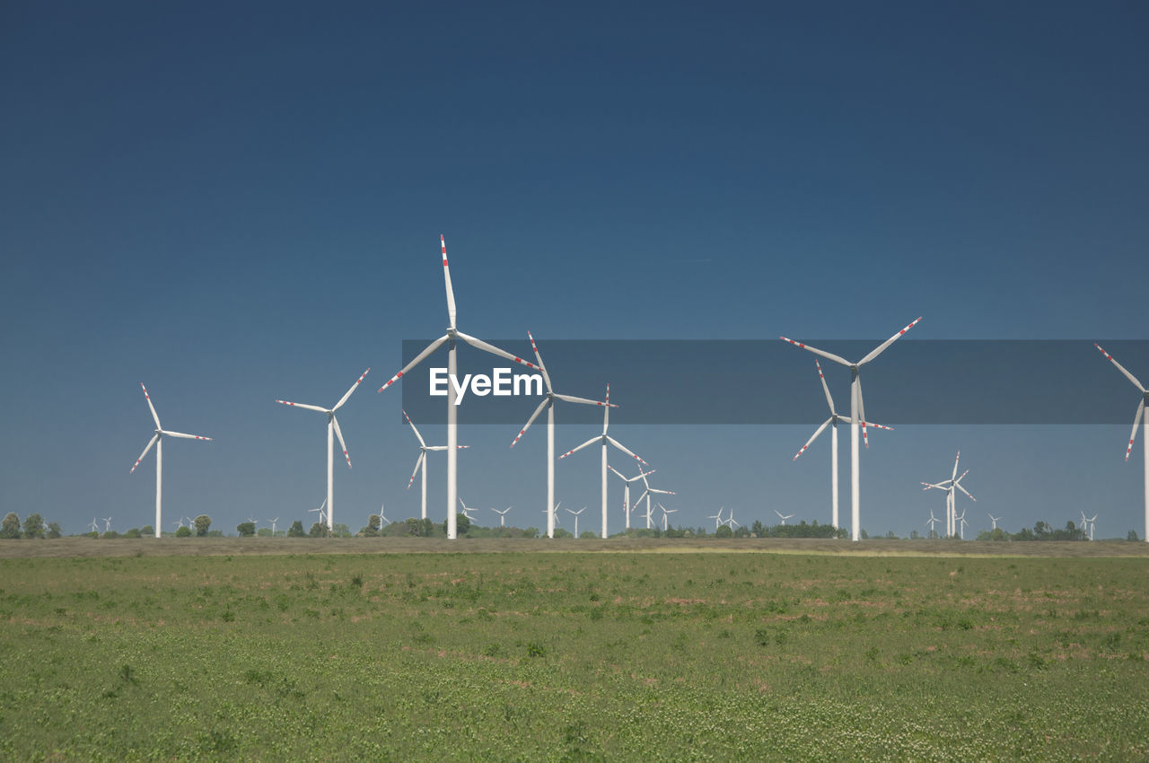 Wind turbines on field against clear sky