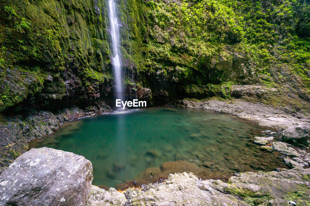 SCENIC VIEW OF WATERFALL AGAINST ROCKS