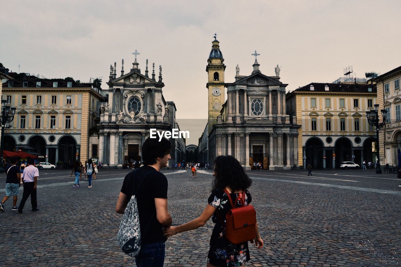 Couple walking against buildings in city