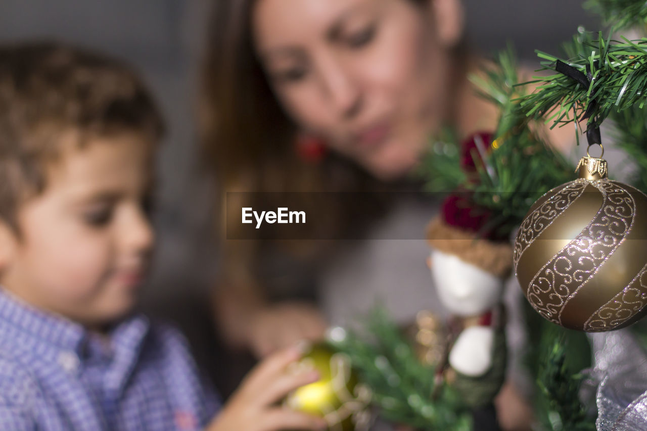 Mother and son decorating christmas tree at home