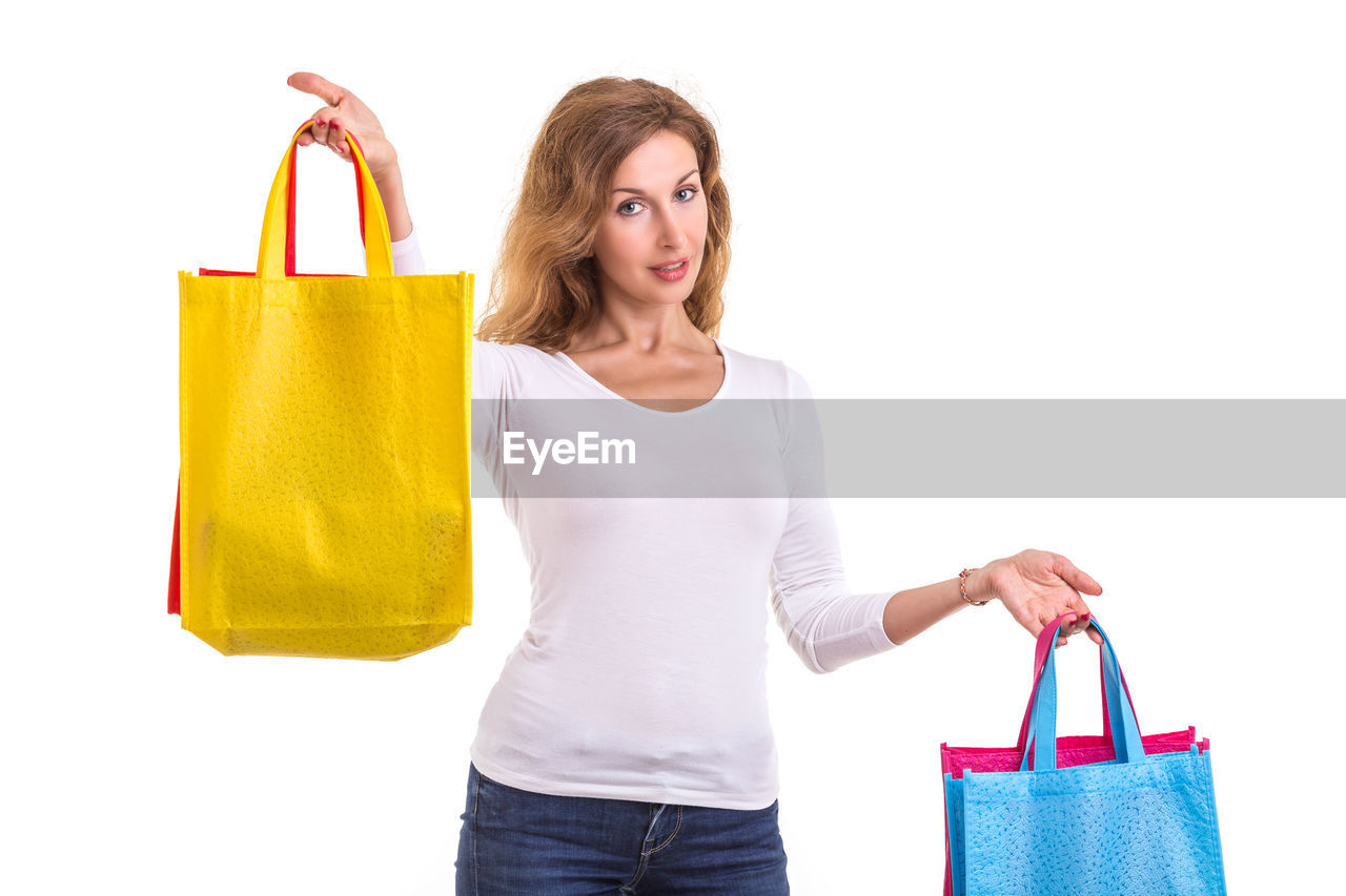 Portrait of woman holding shopping bags against white background